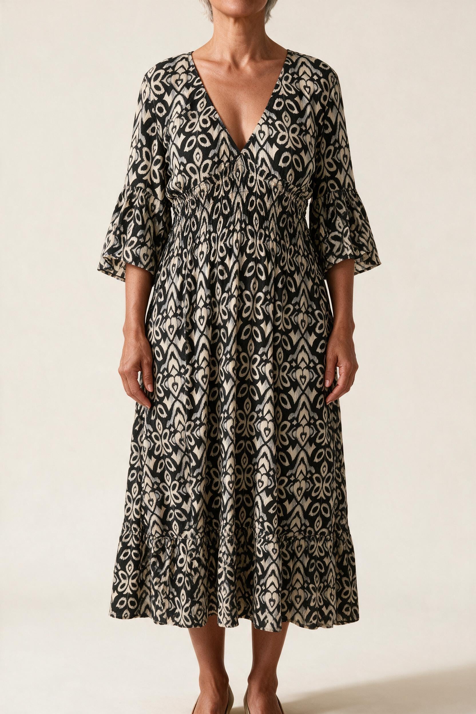 Robe midi Roseline, coloris noir — imprimé ikat, col en V, taille smockée et manches 3/4 à volant, vue de face