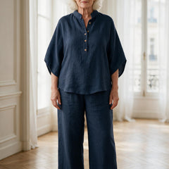 Femme de 70 ans portant l'ensemble Clarisse en lin bleu marine, tunique à col montant et pantalon large, dans un appartement parisien