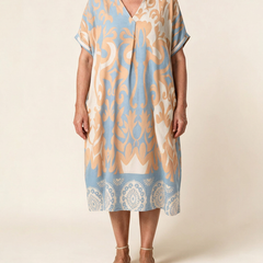 Robe midi Célestine en Bleu Horizon, vue de face sur fond crème — coupe ample, col en V, bordure à médaillons