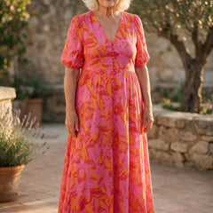 Femme de 70 ans portant la robe longue Salomé à imprimé floral rose et orange, sur une terrasse du sud de la France