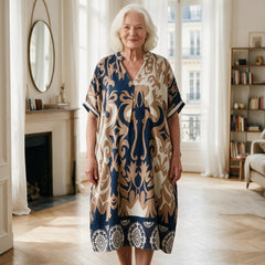 Femme de 70 ans portant la robe midi Célestine à imprimé ornemental bleu marine et beige, dans un appartement parisien